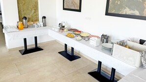 Distribución tipo bufé con diversos alimentos y bebidas, una cafetera y un tostador.