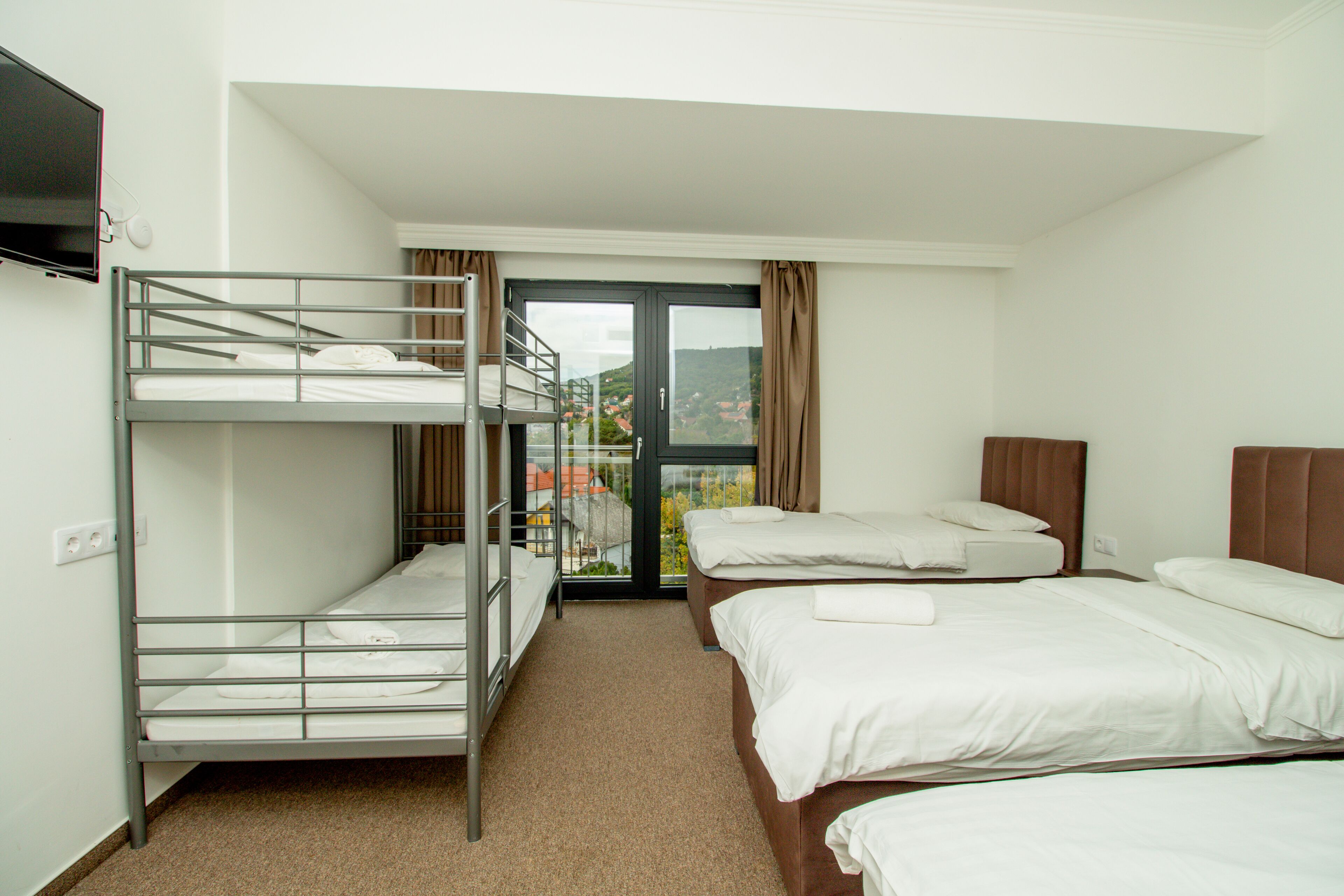 Habitación de hotel con literas, una cama individual y un televisor en la pared.