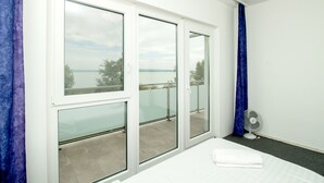 Habitación de hotel con un amplio ventanal corredera que da a un balcón con vista al mar.