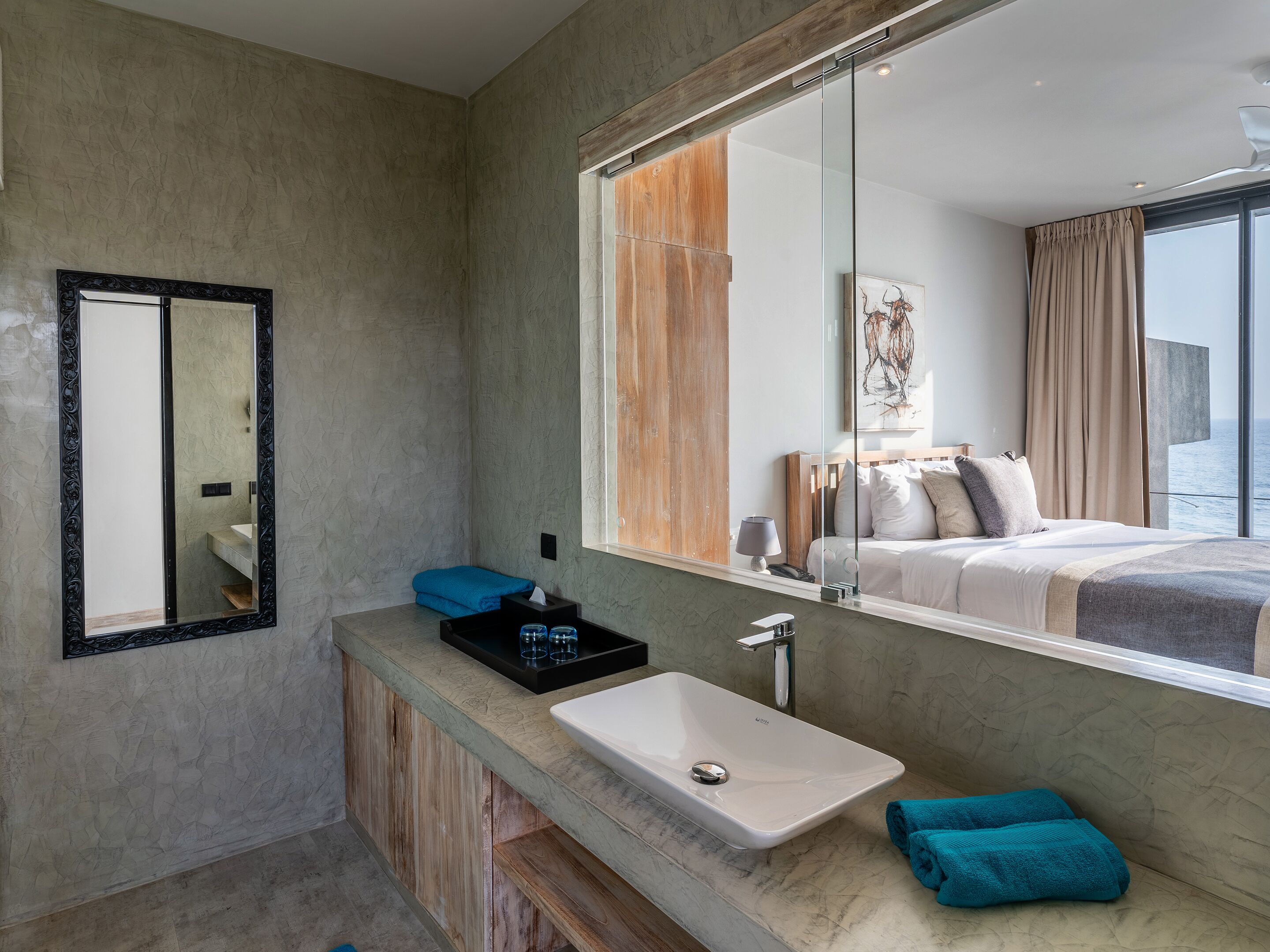 A modern bathroom with a large mirror, a white sink, and a wooden vanity.