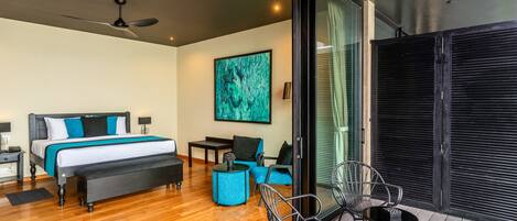 A modern hotel room with a large bed, a desk, and a balcony with chairs.