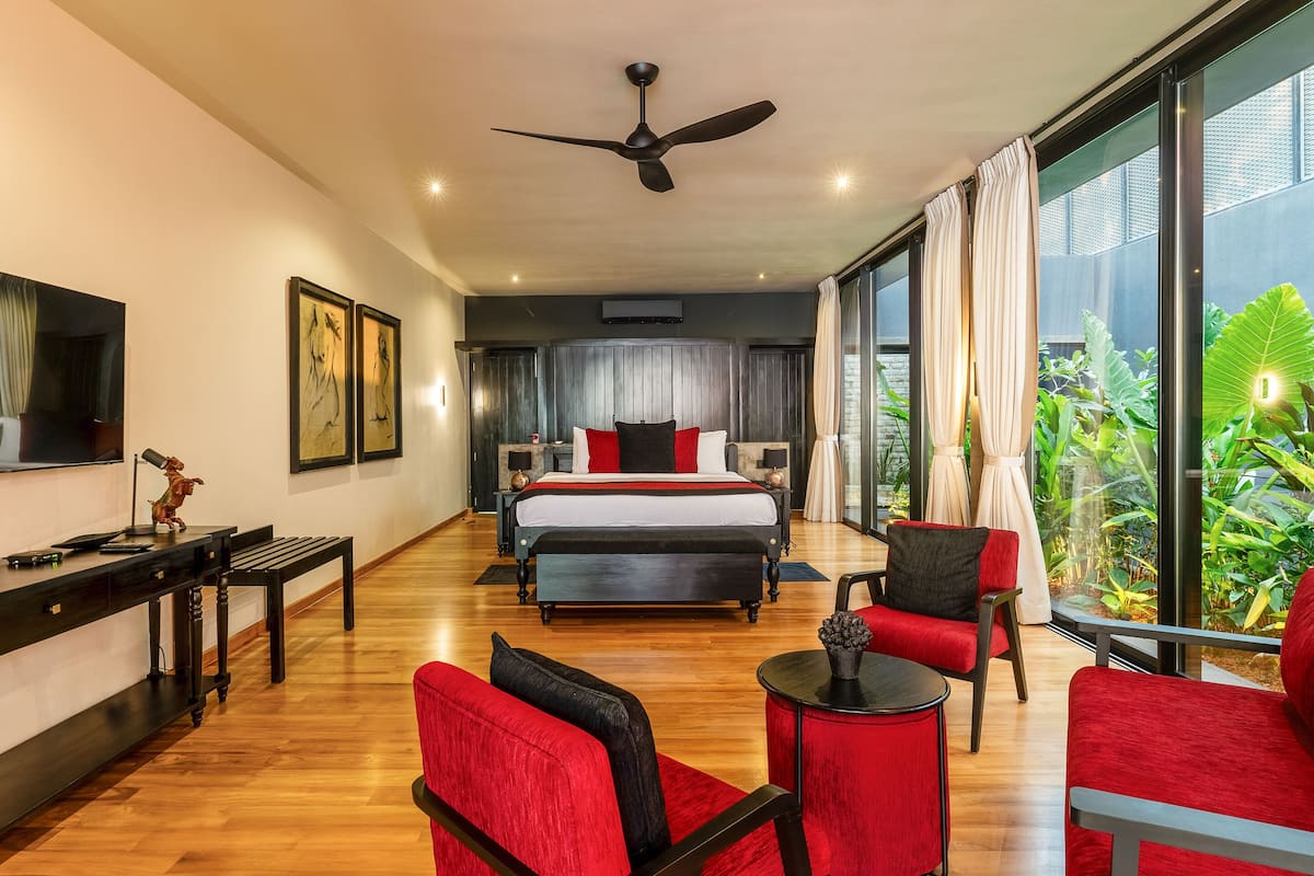 Une chambre d’hôtel moderne dotée d’un grand lit, d’un bureau, d’une chaise et offrant une vue sur la verdure grâce à de grandes fenêtres.
