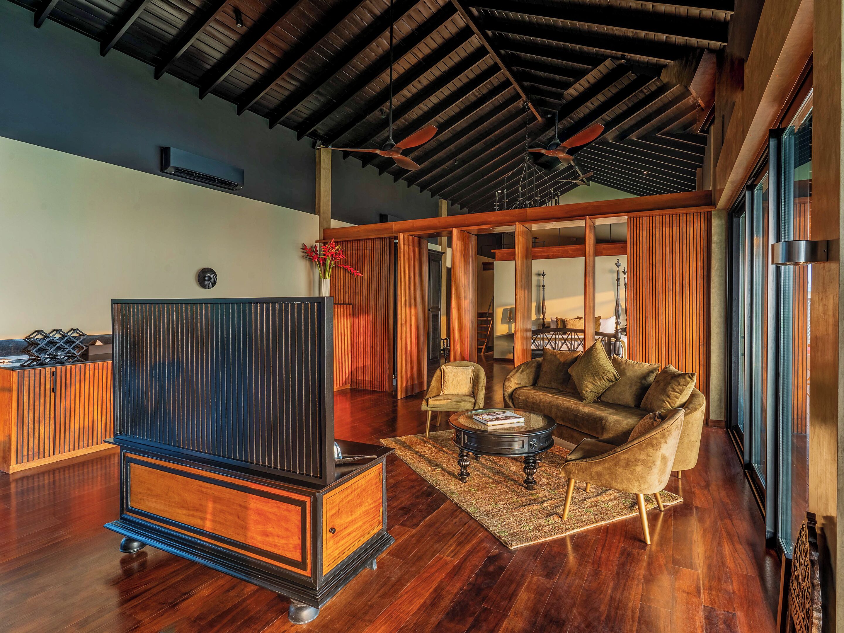 A spacious living area with a wooden floor, a large dark wooden cabinet, a sofa, and a coffee table.