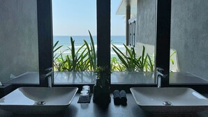 Une salle de bain avec deux lavabos et vue sur l’océan.