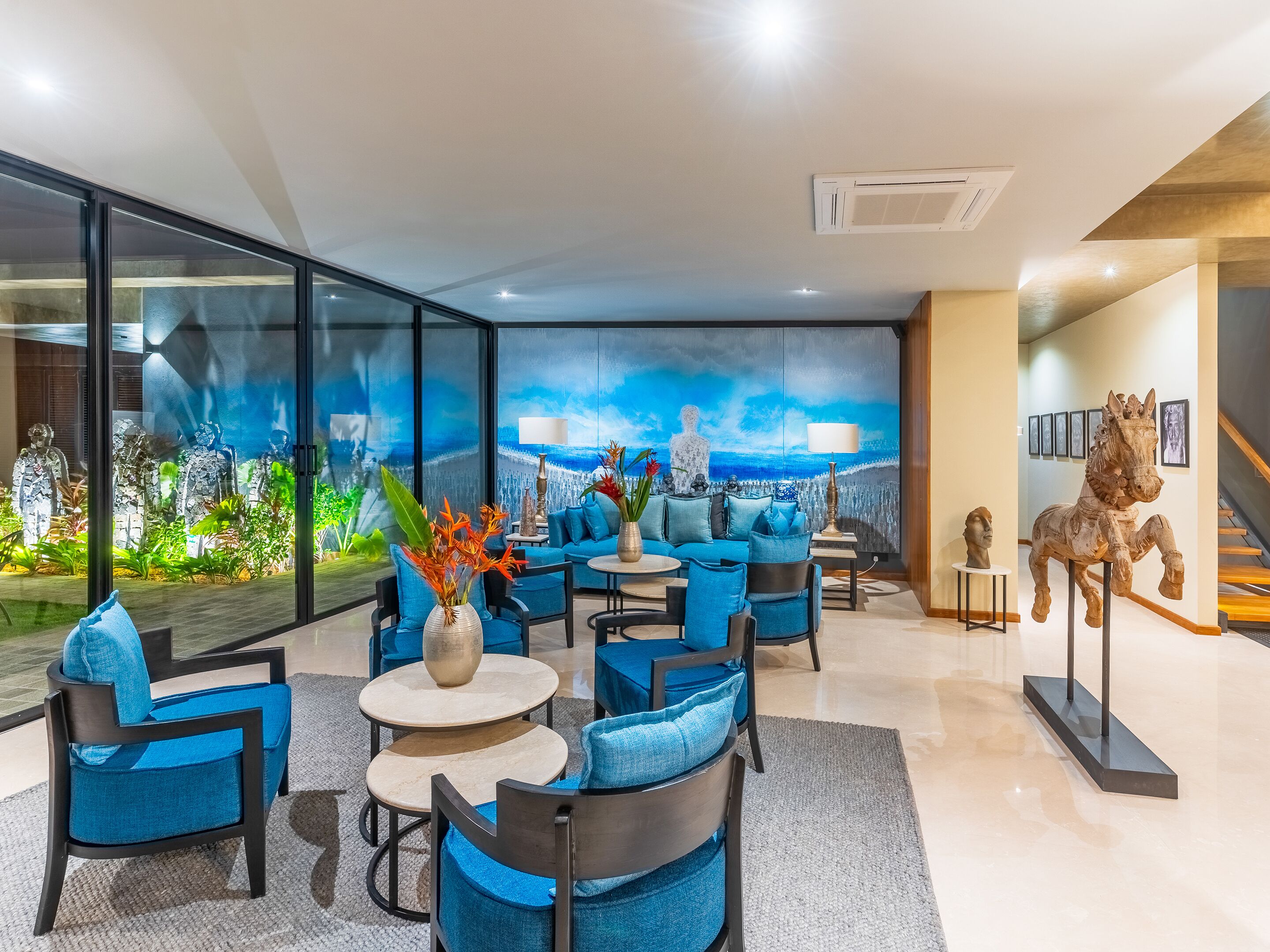 A modern lounge area with blue furniture, a cityscape mural, and a sculpture of a horse.