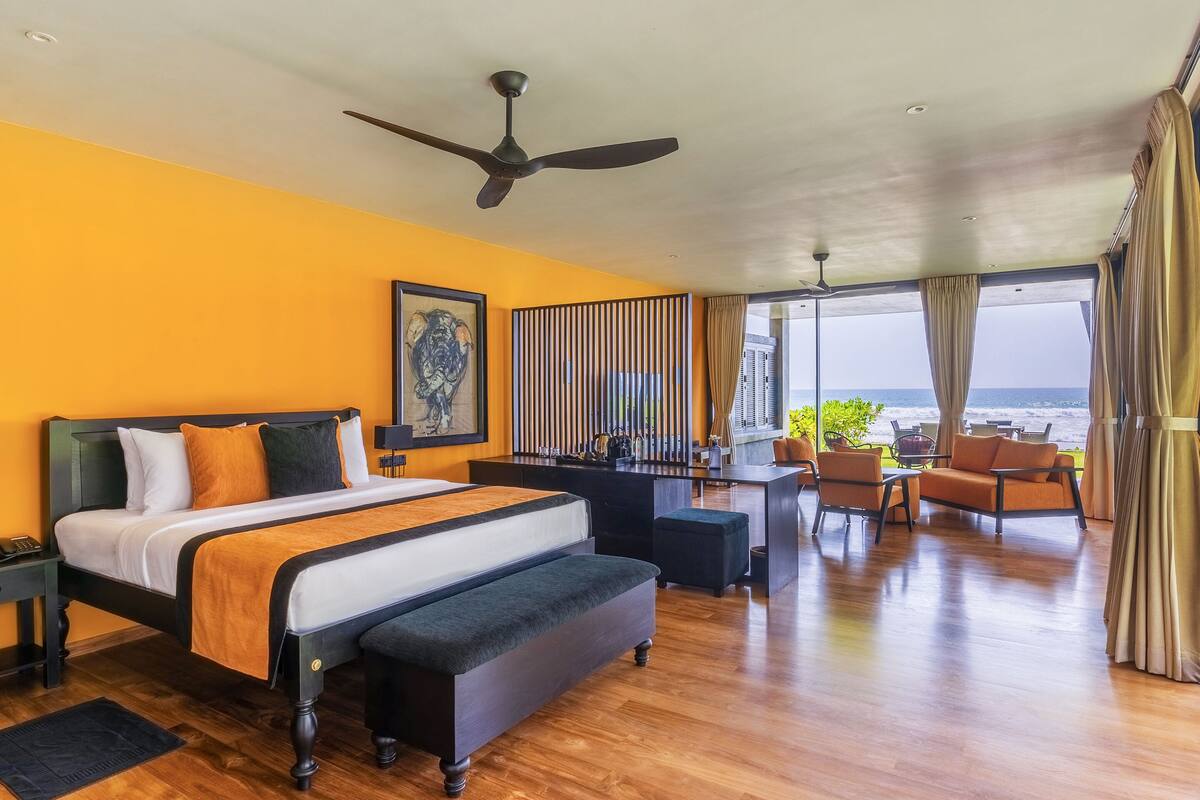 Une chambre spacieuse avec un grand lit, un bureau et une vue sur l’océan.