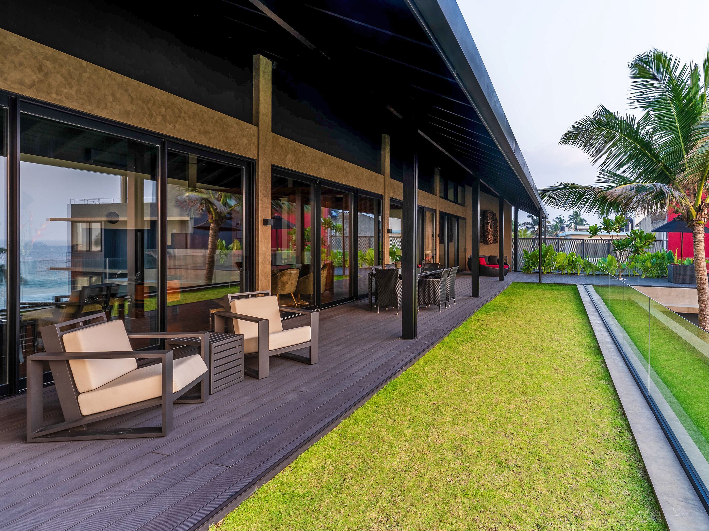 Une terrasse extérieure moderne, dotée d’un espace salon, d’une pelouse et offrant une vue sur l’océan.