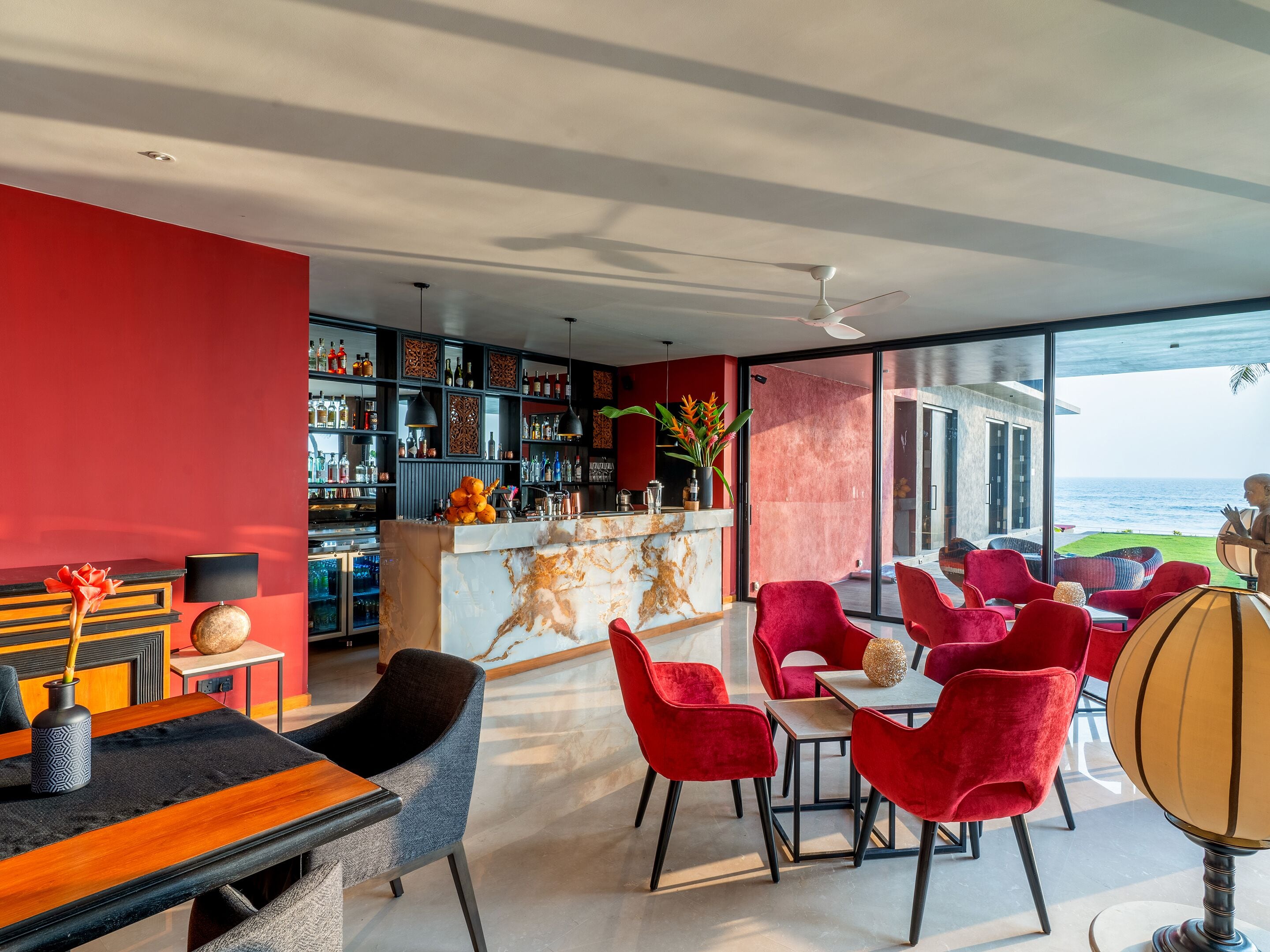 A modern interior with a bar area, red and black decor, and a view of the ocean.