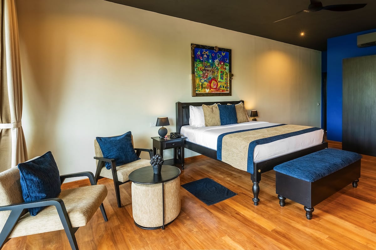 Une chambre d’hôtel avec un lit, une chaise, une petite table et un tableau au mur.