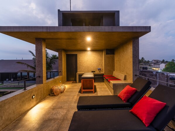 Eine moderne Lounge im Freien mit einer Couch und Sesseln, einem kleinen Tisch und Blick auf die umliegenden Gebäude.