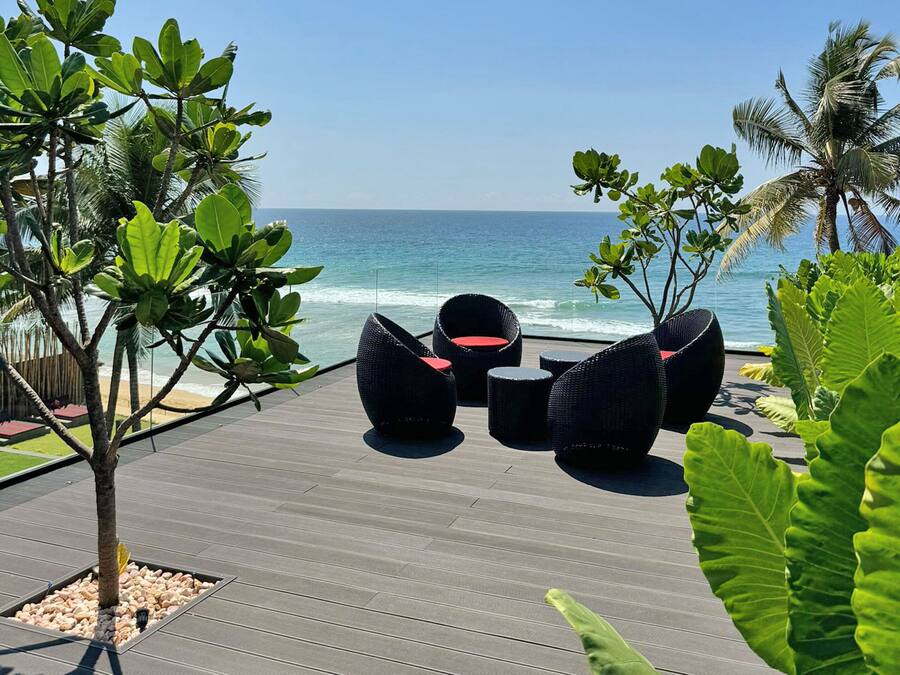 An outdoor seating area with wicker furniture and a view of the ocean.