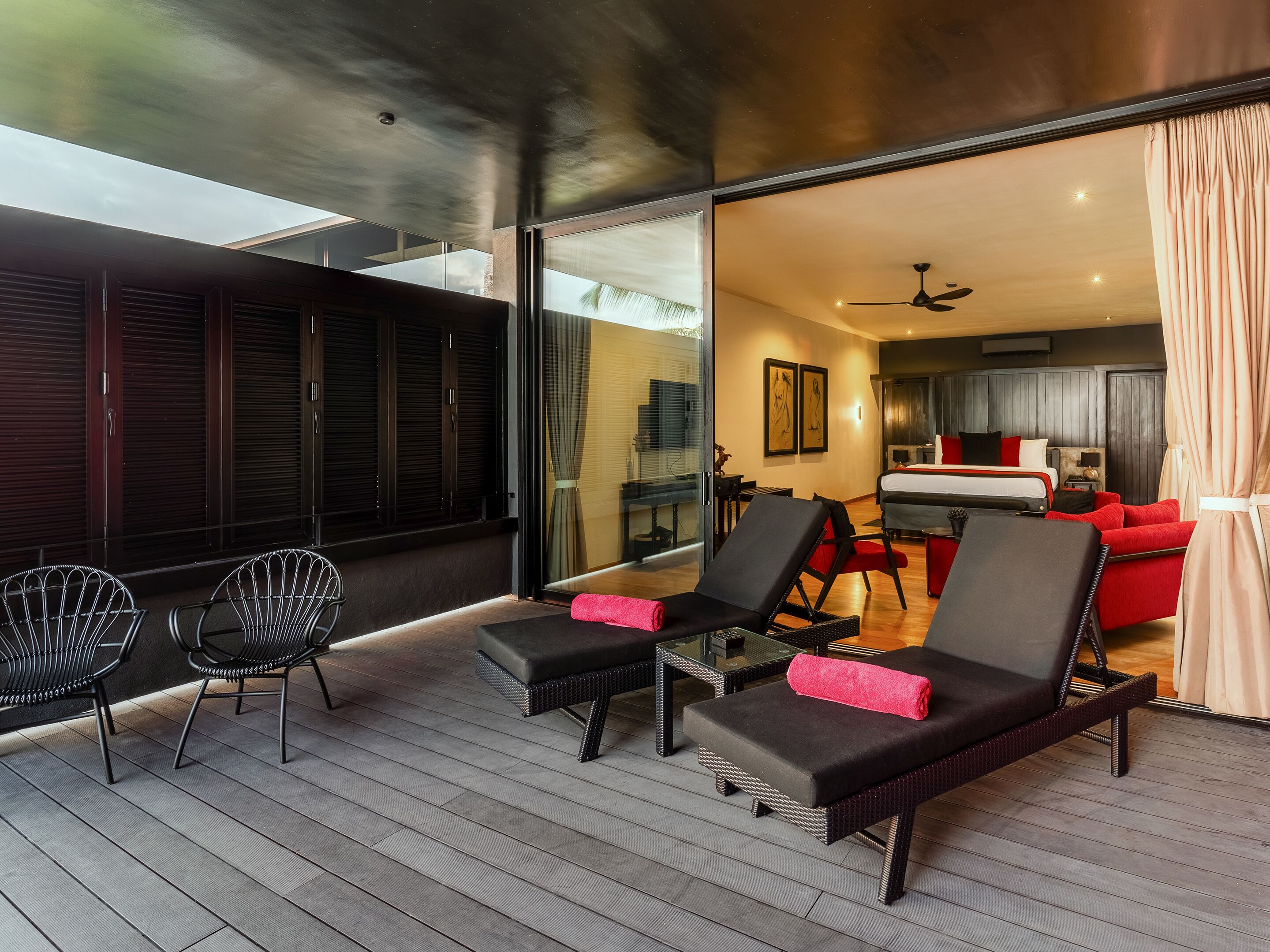 Et moderne hotelværelse med balkon, seng, rød sofa og spiseplads.