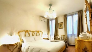 A hotel room with a large bed, a bedside table, a dresser, and a chandelier. - Ca' Perdon Apartment (Venezia)