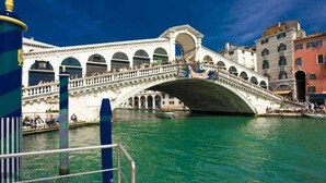 A historic stone bridge with multiple arches spanning a body of water, surrounded by buildings with classical architecture. - Ca' Perdon Apartment (Venezia)