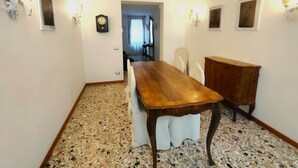 A hallway with a wooden dining table, white chairs, and a wooden cabinet. - Ca' Perdon Apartment (Venezia)