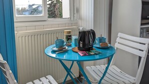 A small room with a window, a table with a kettle, a mug, and a chair.