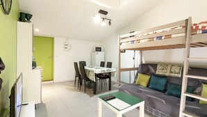 A compact living space with a bunk bed, a dining area, and a kitchenette.