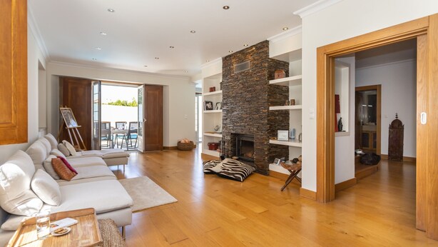 A spacious living room with a stone fireplace, a sofa set, and a wooden floor. - Casa Das Azeitonas (Azeitão)
