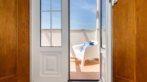A wooden door leading to a balcony with a white chair and a blue towel. - Casa Das Azeitonas (Azeitão)