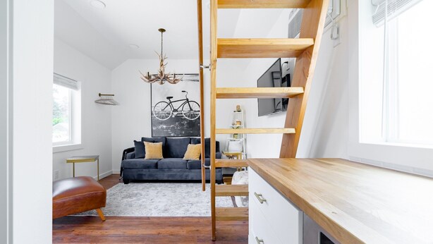 A modern living room with a black sofa, wooden shelves, and a bicycle wall art. - Urban Tiny House near Portland & Columbia Gorge (Camas)