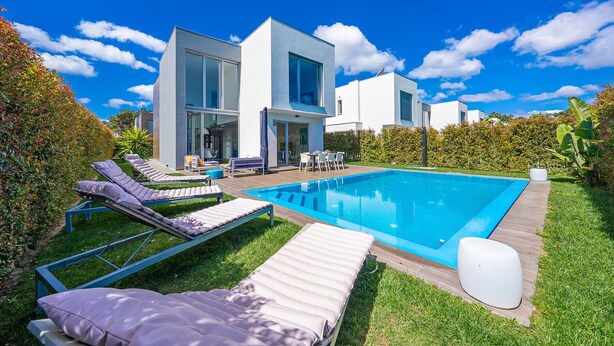 A modern house with a swimming pool, lounge chairs, and a patio area. - Casa Nilo Design - Villa with pool near the beach (Aroeira)