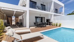 Une maison moderne à deux étages dotée d’une piscine, d’un espace extérieur aménagé et d’un coin barbecue.