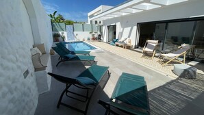 A modern outdoor pool area with lounge chairs and a glass-enclosed patio. - Casa Evae (Azeitão)
