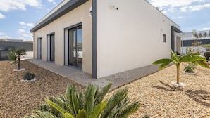 A modern building with a flat roof, large windows, and a paved entrance area. - Casa Evae (Azeitão)