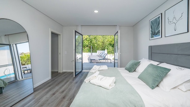 Ett modernt hotellrum med en stor säng, en balkong och utsikt över omgivningarna.