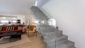 Un salon moderne avec un escalier en verre menant à un niveau supérieur.