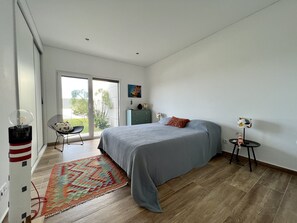 A bedroom with a bed, a chair, a desk, and a window.