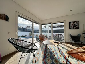 Un salon moderne doté d’une grande porte vitrée donnant sur un balcon, d’une table ronde et de deux chaises.