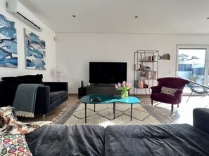 Un salon moderne avec un téléviseur à écran plat, un canapé, une table basse et une bibliothèque.