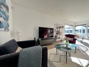 A modern living room with a flat-screen TV, a sofa, a glass coffee table, and a bookshelf. - Casa Marido - Villa with swimming pool (Pinhal do Cabedal)