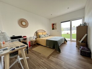 Une chambre à coucher comprenant un lit, un bureau, une chaise et donnant sur l’extérieur.
