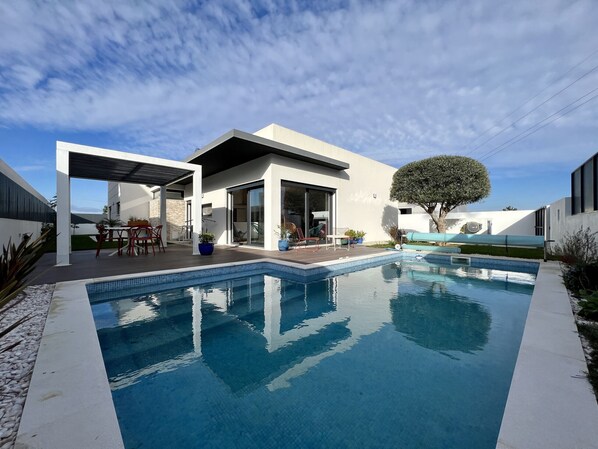 A modern house with a swimming pool, a covered patio, and a large tree. - Casa Marido - Villa with swimming pool (Pinhal do Cabedal)