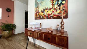 A modern living room with a wooden console table, a large abstract painting, a potted plant, and a clock on the wall. - Casa Marido - Villa with swimming pool (Pinhal do Cabedal)