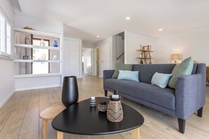A modern living room with a grey sofa, a black coffee table, and a wooden floor.