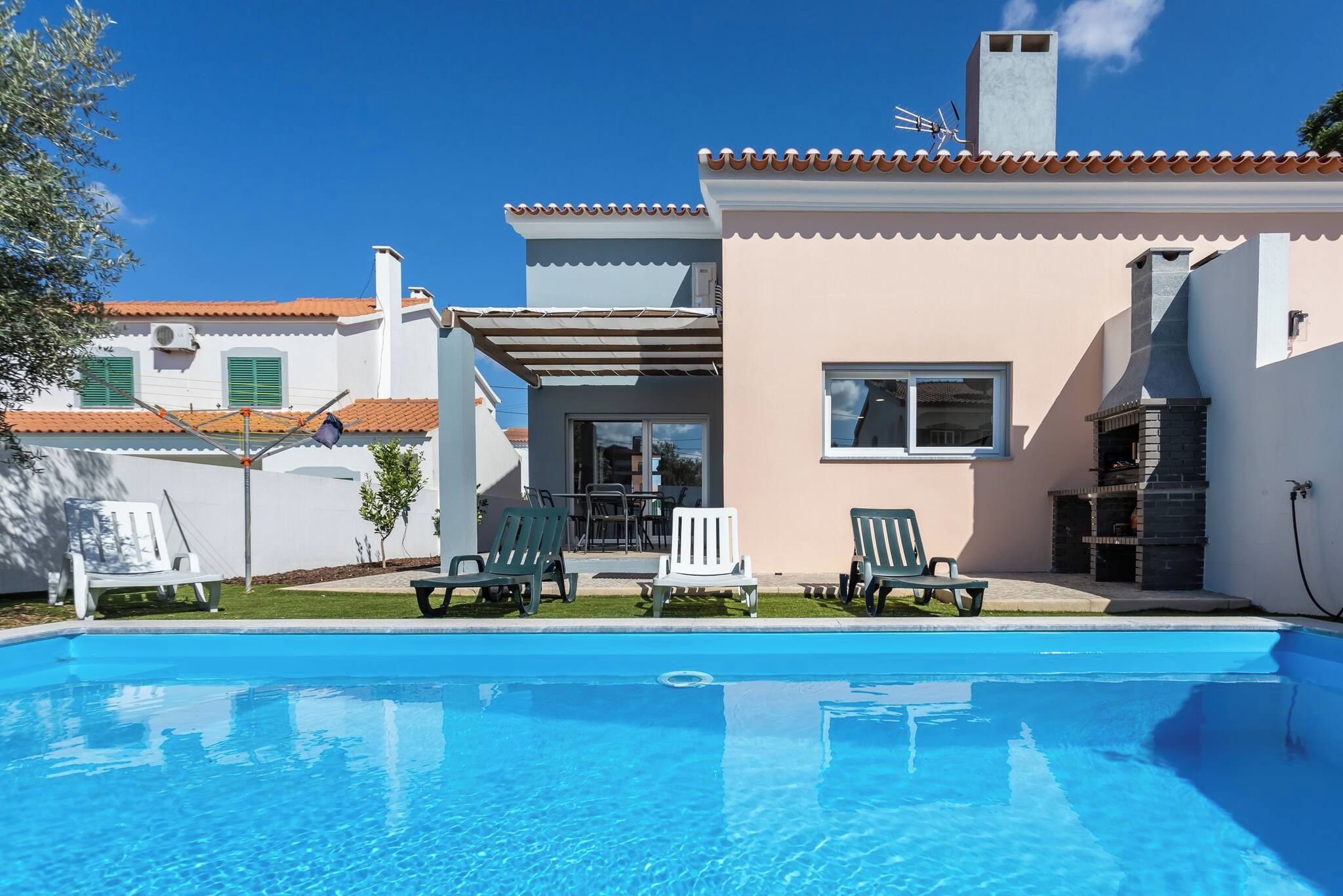 A swimming pool with lounge chairs, a patio area, and a building with a chimney.