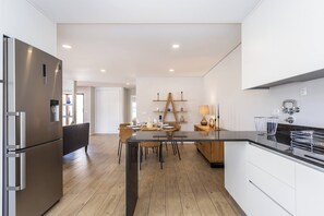 A modern kitchen with a central island, wooden flooring, and white cabinetry.