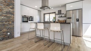 Une cuisine moderne dotée d’un îlot central, d’appareils électroménagers en acier inoxydable et d’un mur d’accent en pierre.