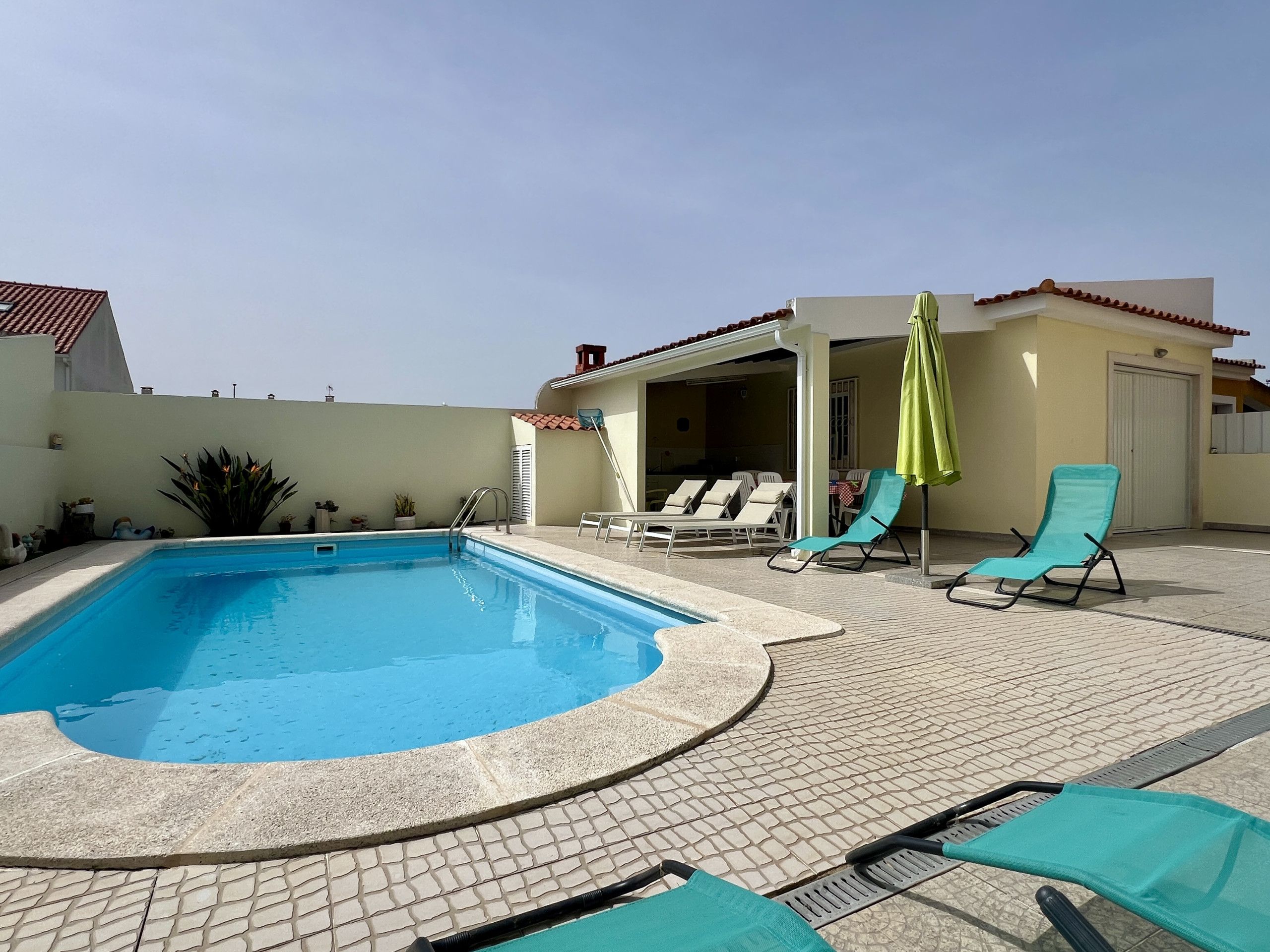 A swimming pool with lounge chairs and a covered patio area.