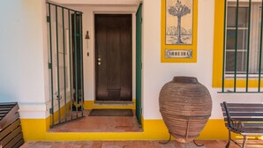 A building entrance with a green gate, a large metal pot, and a bench. - Casa D'Aroeira - Serra d'Arrabida (Azeitão)