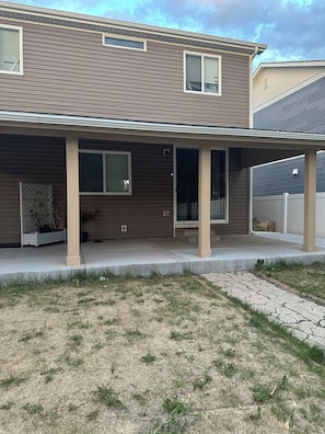 A two-story house with a covered porch, a front door, and a small side entrance.