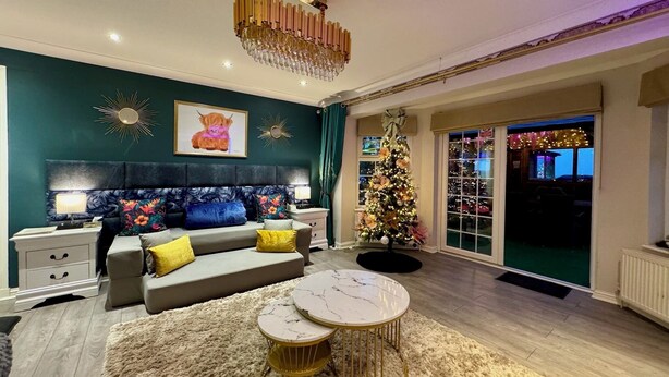 A modern living room with a sofa, coffee table, and a Christmas tree. - FINN VILLAGE Raspberry Cottage HOT TUB Gazebo Private Garden (Glasgow)