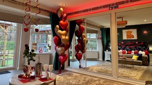A room with a large, decorative balloon arrangement, a chandelier, and a view of the outdoors through large windows. - FINN VILLAGE Raspberry Cottage HOT TUB Gazebo Private Garden (Glasgow)