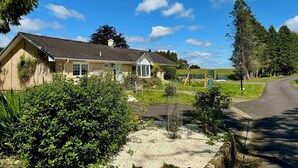 A two-story house with a sloped roof, a front porch, and a swing set in the yard. - FINN VILLAGE Raspberry Cottage HOT TUB Gazebo Private Garden (Glasgow)