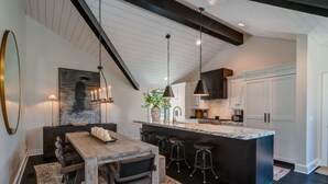 Una cucina moderna con isola in marmo, illuminazione a sospensione e mobili in legno scuro.