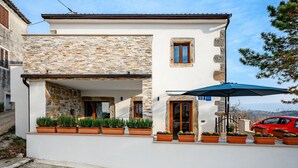 Un edificio con facciata in pietra, una porta in legno e piante in vaso al piano terra.