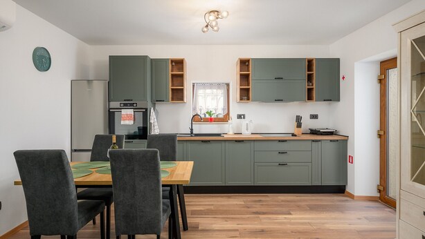 Una cucina moderna con mobili grigi, un tavolo da pranzo in legno e sedie.